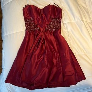 I am selling a strapless burgundy dress, with a mesh flower design on the waist.